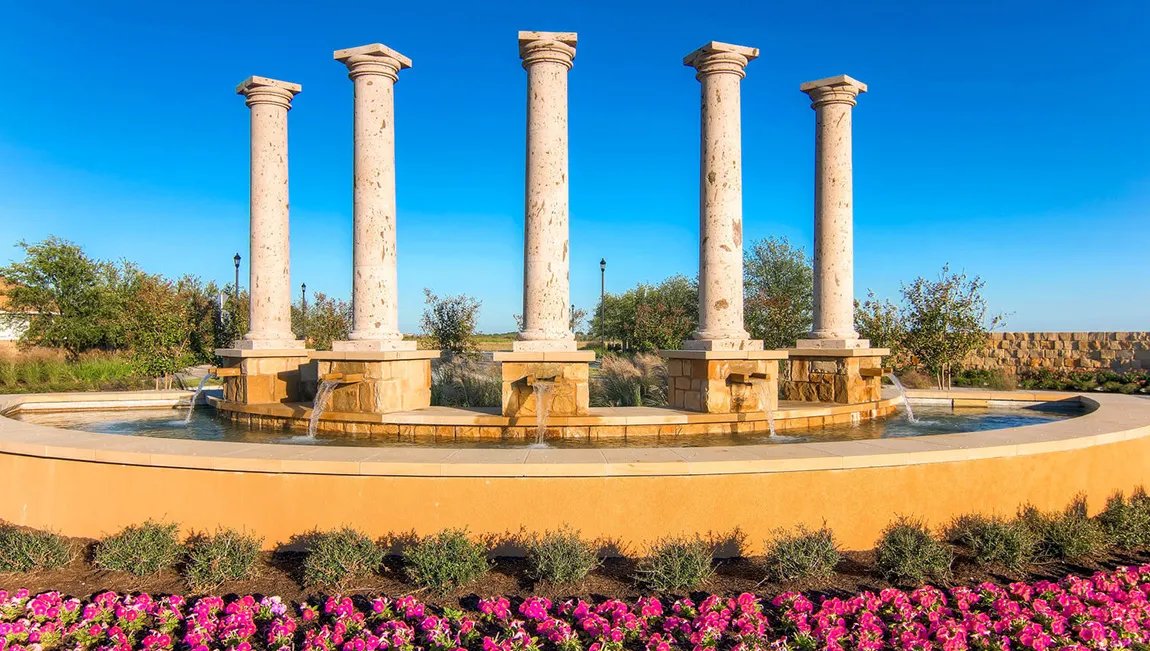 The Sorento community entrance: stone columns and fountain under a blue Texas sky
